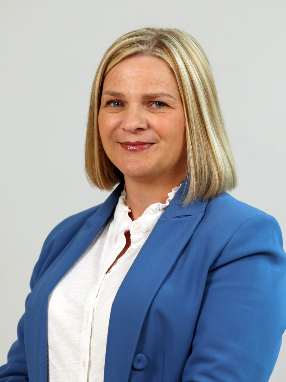 lady with blonde shoulder length hair, blue jacket and white blouse